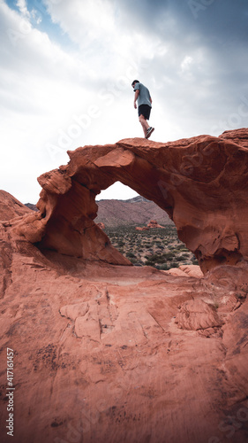 A guy standing on a arches in the valley of fire state park, USA