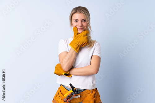 Electrician woman over isolated blue background laughing