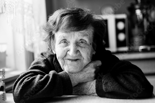 Portrait of an old woman in her home. Black and white photo.