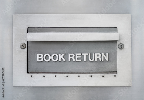 Outdoor book return drop slot from library. Large metal drawer or opening with embossed letters "book return" with key locks for anti-theft and safety. The drawer is mounted in a metal wall.