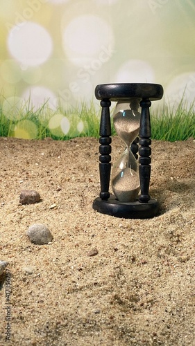 an hourglass measuring the time standing on the sand 