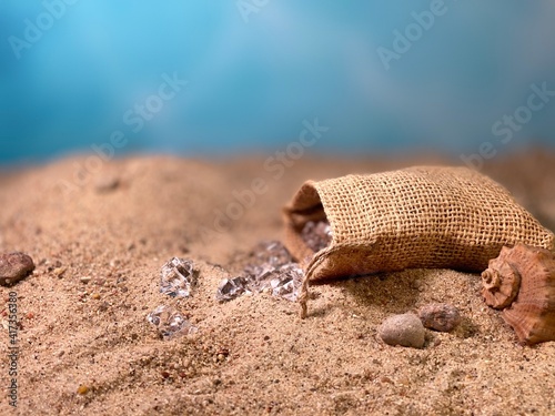 Crystals falling out of the jute bag on the sand visible stones and shells