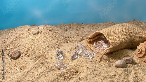 Crystals falling out of the jute bag on the sand visible stones and shells