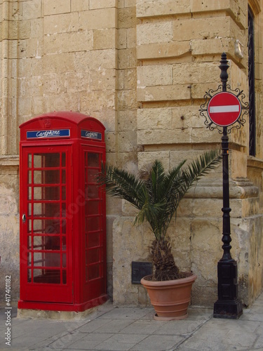 Stara czerwona angielska budka telefoniczna przy murowanej ścianie ze znakiem stop
