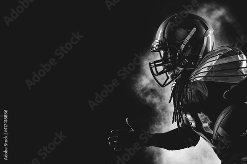 American football player. Sportsman with ball in helmet on stadium in action.