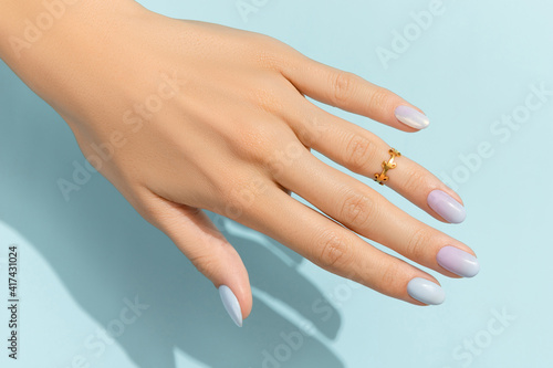 Womans hands with trendy manicure on blue background. Summer nail design