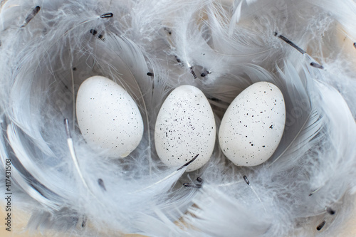 Białe nakrapiane wielkanocne jaja otoczone piórami, wielkanoc