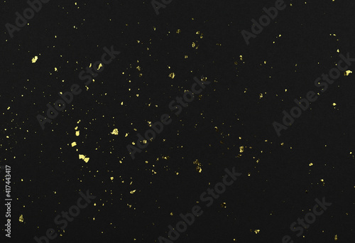 Gold flakes of potal on black textured paper