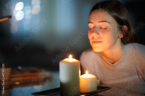 Woman smelling a lighted candle in the night