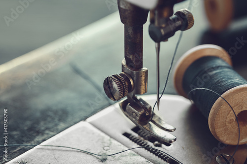 Close up of sewing needle. Spool of thread on working part of antique sewing machine.