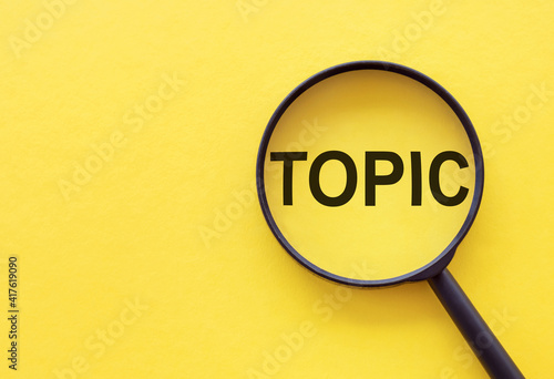 The word TOPIC is written on a magnifying glass on a yellow background.