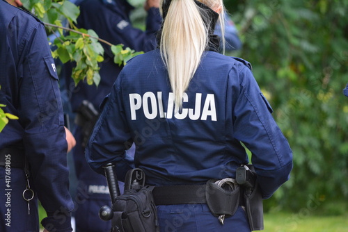 Blond policjantka na patroluje na tle zieleni. 