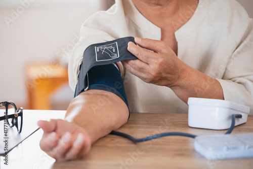 Senior woman is checking blood pressure and heart rate with digital pressure gauge by herself at home.Older woman taking care for health. Health and Medical concept.