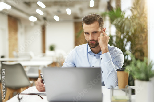 Handsome office clerk at his workplace with coffee and gadget