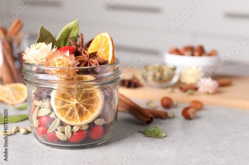 Aromatic potpourri in glass jar on light table. Space for text