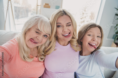 Photo portrait of different generations women taking selfie grimacing fooling showing tongues at home silly faces