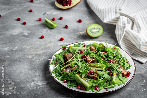 Fresh salad with chicken liver, kiwi and pomegranate, arugula. Top view