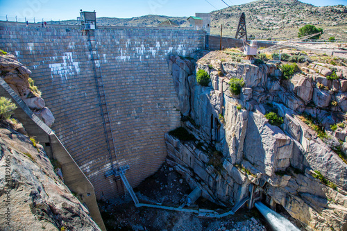 Alcova, Wyoming - 6/27/2018: Pathfinder dam, with water exiting the power house, constructed in 1909 of granite stone blocks, near Alcova, Wyoming.