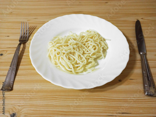 homemade noodles (spaghetti) pasta with butter in a white plate on a wooden background. Copyspace