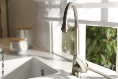 Water drops falling down from tap in kitchen