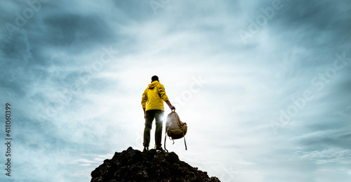 Successful man standing on the top of the mountain at sunset - Hiker with backpack extreme climbing - Sport success and inspirational concept