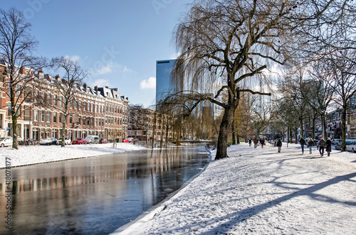 Rotterdam, The Netherlands, February 10, 2021: Spoorsingel canal in Provenierswijk neighbourhood, with ice and snow and in the background the downtown highrise