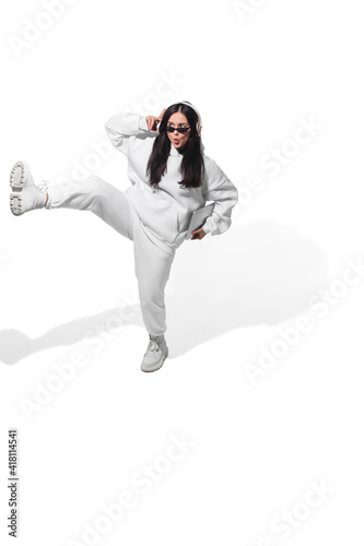 Dancing with headphones. High angle view of young woman on white studio background. Human emotions and facial expressions concept. Full length portait, copyspace for ad. Fashion, retro style.