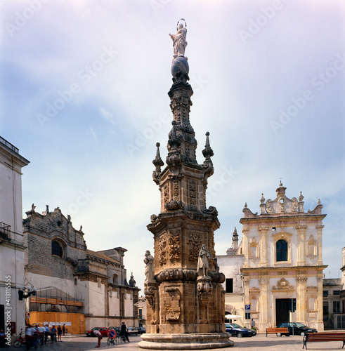 Nardò, Lecce. Guglia dell'Immacolata in Piazza Salandra con la chiesa di San Tritone.