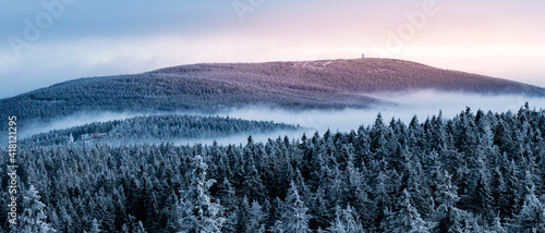 A view from the Orlica observation tower to the mountains with a snow-covered forest and an incoming fog.
