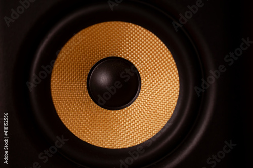 A black and gold coloured speaker cone.Shot with soft golden glow lighting.