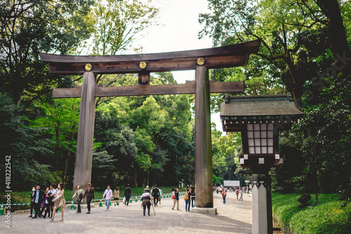 Traditional wooden lamp and great torii gate and tourist and visitors at Meiji Shrine in Yoyogi Park, Tokyo, Japan