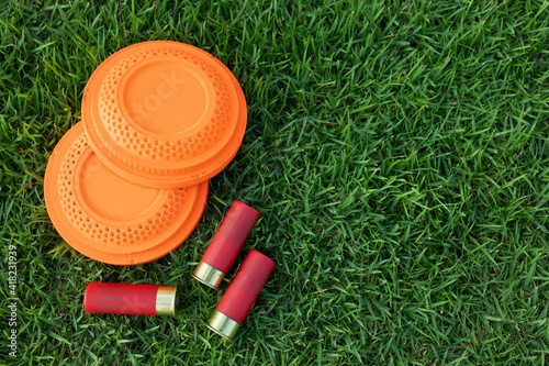 Clay disc flying targets and shotgun shells on green grass background ,Clay Pigeon target