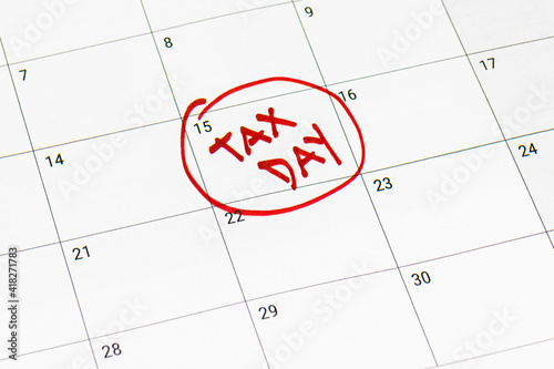 Tax day marked on April 15 calendar with red marker. Deadline for 1040 form return.