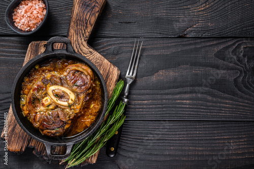 Stew veal shank meat OssoBuco, italian osso buco steak. Black wooden background. Top view. Copy space