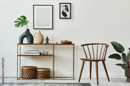 Stylish concept of living room interior with mock up poster frames, wooden console, chair, tropical leaf in vase, rattan baskets, plant, carpet and personal accessories in home decor. Template.