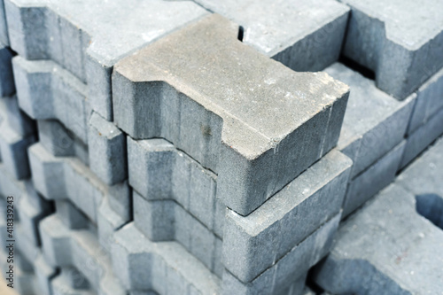 Gray paving stones for the construction of footpaths. Cement material for laying sidewalks in a store warehouse. Trade in blocks with technological slots in the wholesale and retail network. Close-up