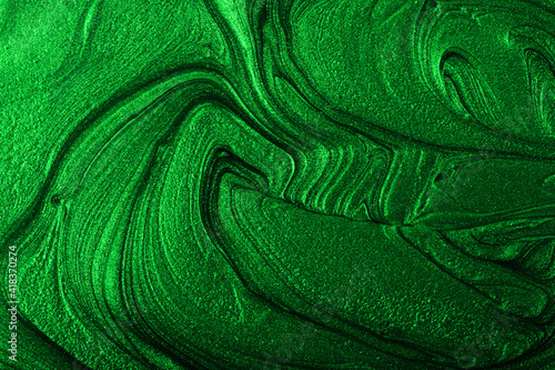 Beautiful emerald green stains of liquid nail polish,fluid art technique.Monochrome marble background.Liquid stripy paint texture.Nail lacquer flow modern backdrop. Minimalism concept.Copy space.