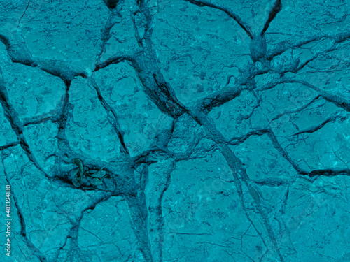 Rough textured light turquoise cosmic blue matte abstract stone with cracks and relief background. Wall