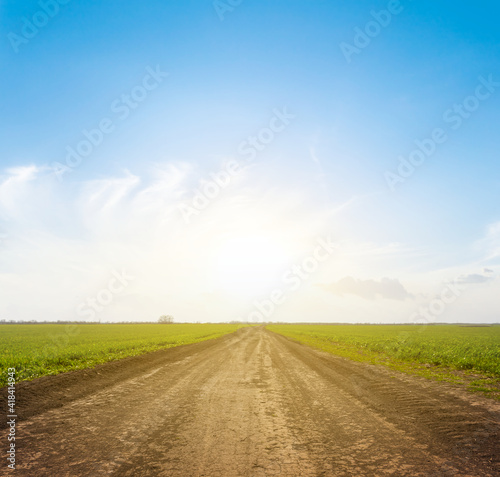 ground road among green fields at the sunset, countryside rural background