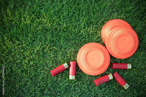 Clay disc flying targets and shotgun shells on green grass background ,Clay Pigeon target