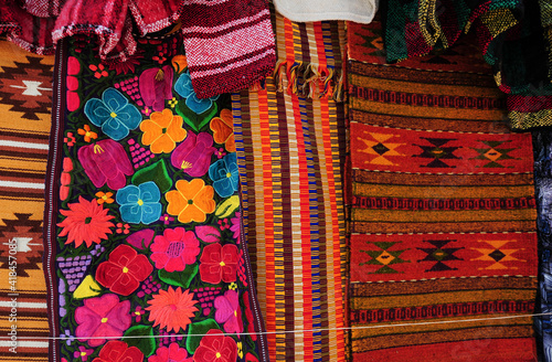 Colorful table runners with flowery and native symbols designs on display at market