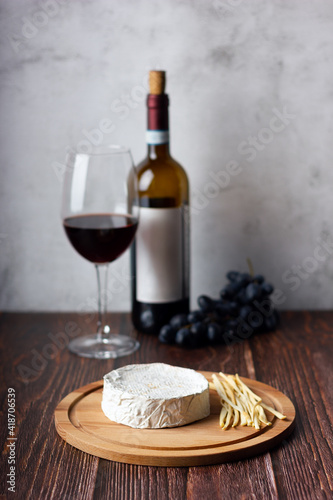 Still life of wine, cheese and grapes on wooden table.