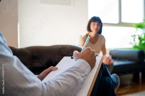 Psychologist taking notes during therapy session.