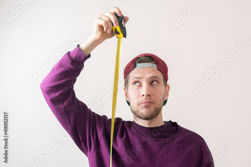 simple adult teenager male person with a roll tape measure the height against the wall