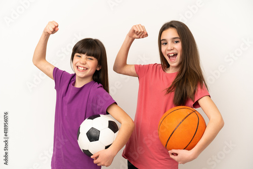 Little sisters playing football and basketball isolated on white background celebrating a victory