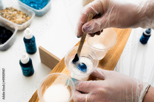 artist stirring blue dye in a plastic cup with epoxy resin