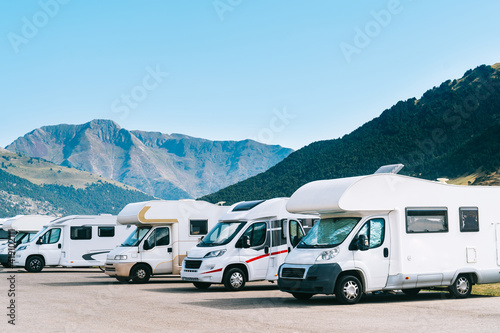 Summer tourism with rv in the mountain. Campers parked in a row in a caravan parking area. Best option for travel feeling free. Motorhomes and campingcar.