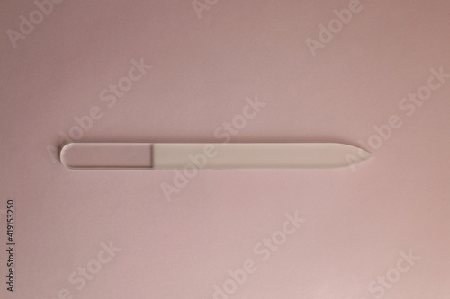 Glass nail file on pink background. Top view.