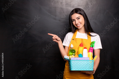 Cheerful housewife with detergents pointing away