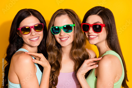Photo of young happy smiling cheerful beautiful cool hipster girls in sunglass isolated on yellow color background